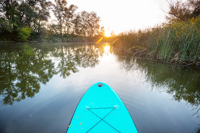 Supboard op een rustig watertje met zonsopgang