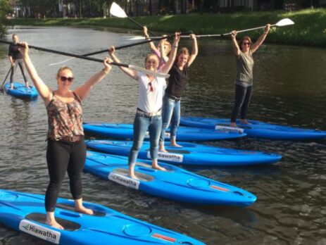 4 personen op een supboard houden hun peddel omhoog