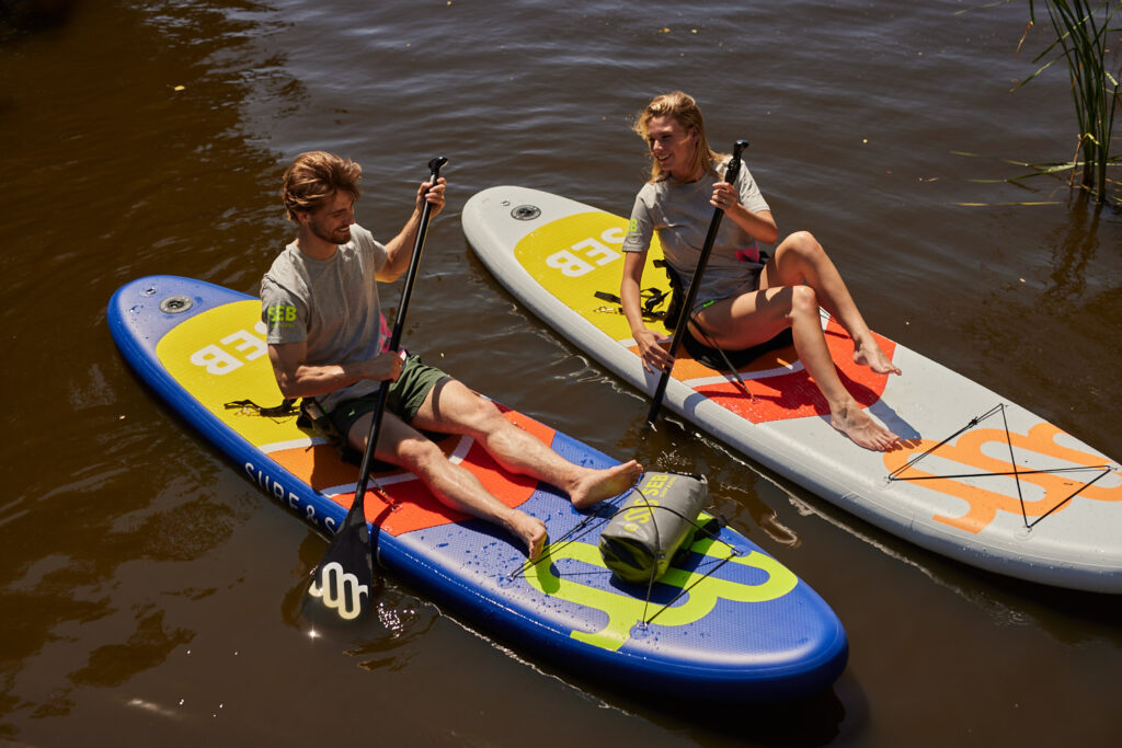 Twee mensen die met een kajakzitje op een SUP board zittend peddelen